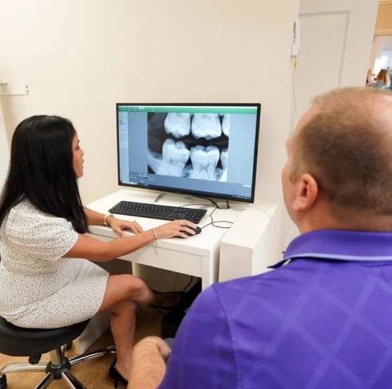 Dentist and assistant reviewing images on a computer screen for emergency dentistry