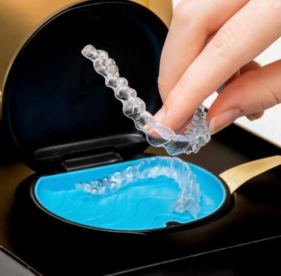 Hand holding a clear invisalign aligner